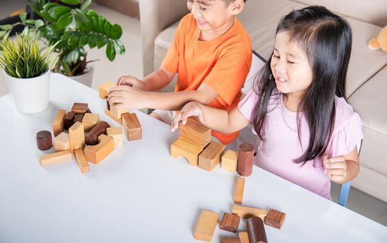 Children boy and girl playing with constructor wooden block building