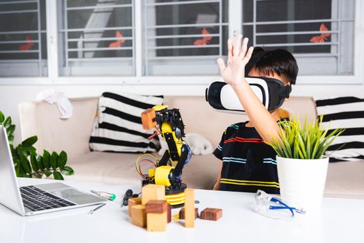 Asian kid boy using VR glasses on robotic arm in workshop