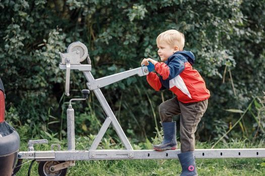 An agile child sports on a boat trailer mechanism in nature