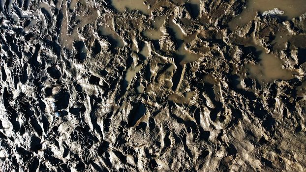 Footprint or imprint shoe in the mud.Mud texture or wet brown soil as natural organic clay and geological sediment mixture as in roughing it in a dirty muddy country ground after the rain or rainy.