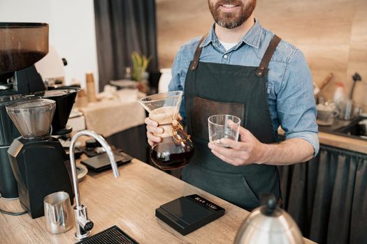 Barista at bar counter with with brewed filtered coffee