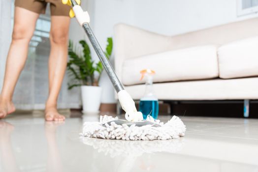 Asian woman washes the floor with a mop and rag indoors