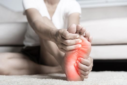 Asian woman feeling pain in her foot at home