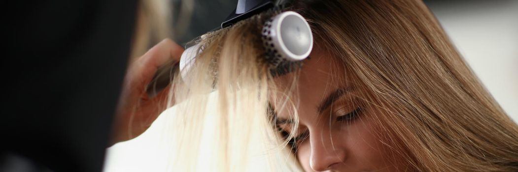 Blonde woman on planned hairdresser appointment get her hair done with hairdryer