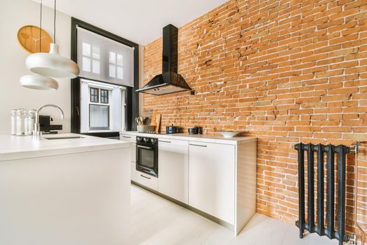 Elegant kitchen design with pendant lamps and brick wall