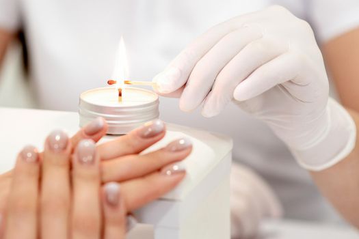 Manicure master is lighting candle