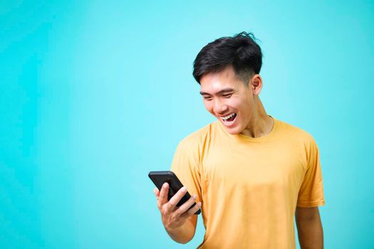 Young Asian man standing of a shocked using mobile phone.