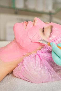 Cosmetologist applying pink alginic mask