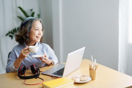 relax time, Portrait of an elderly woman listening to music happily to relax between computer sessions