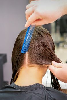 Hairdresser hands parting hair of woman