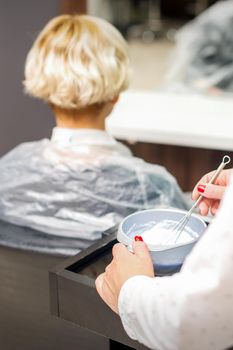 Hairdresser is preparing dye in container