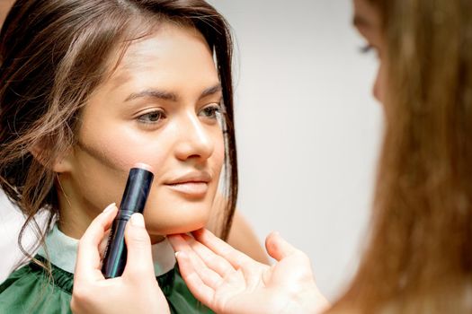 Makeup artist applying cream blush stick