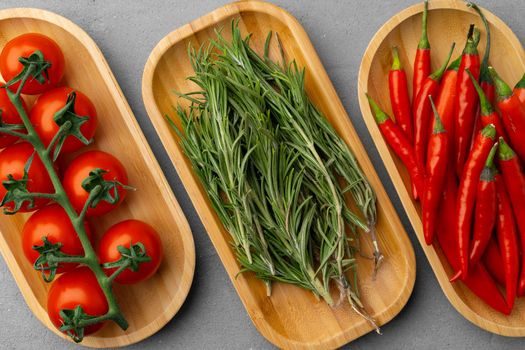 Fresh tomatoes, rosemary and chili peppers on gray background