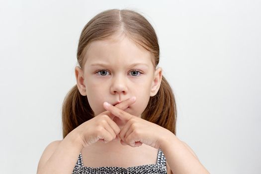Serious child crossed fingers on mouth
