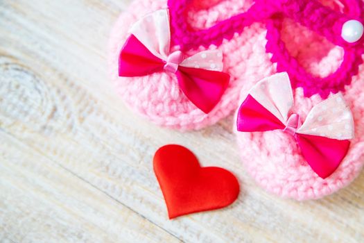 Baby booties and heart on a light background. Selective focus.