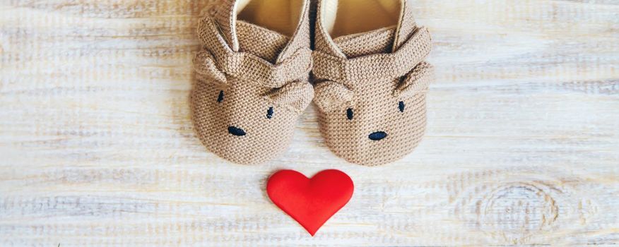 Baby booties and heart on a light background. Selective focus.