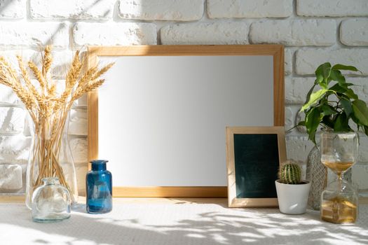 Mockup with a frame and dry flowers in a vase on a white table