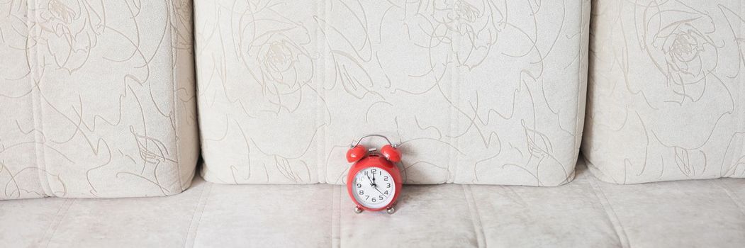 Beige couch and red vintage clock on it show almost midnight