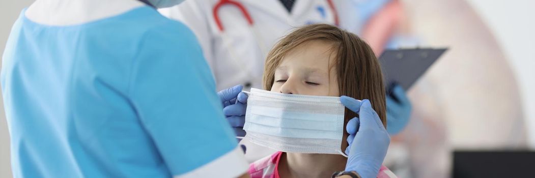 Medical worker put protective mask on little girls face in clinic