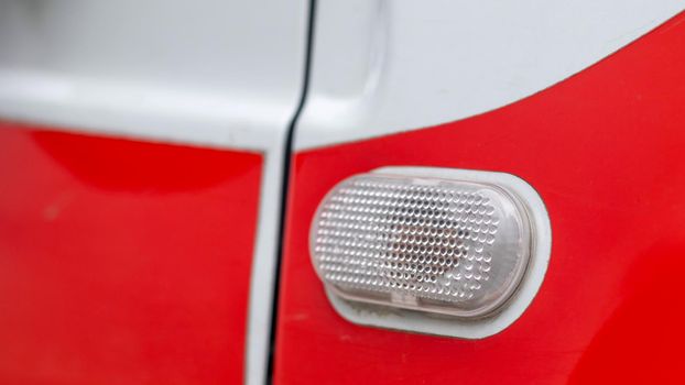 Automotive light bulb. Turn signal on the side of the car. A white turn signal on a red crossover, which is located on the side on the right side of the fender surface.