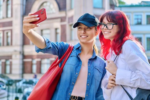 Two beautiful teenage females having fun taking selfie portrait on smartphone