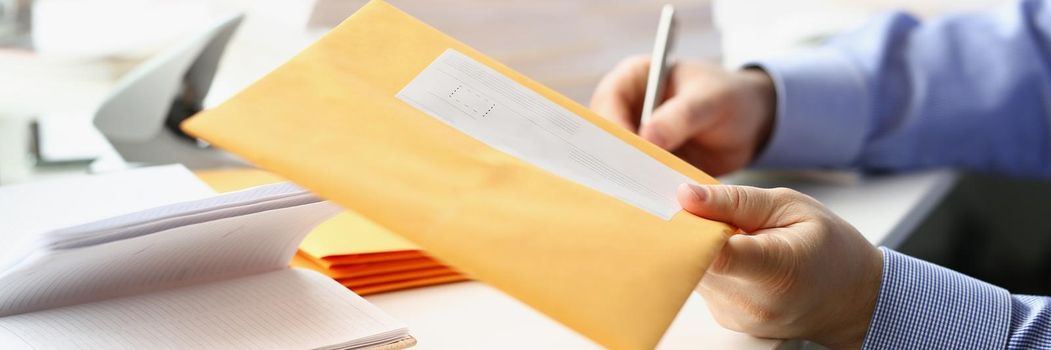 Businessman give envelope to courier for further delivery to address