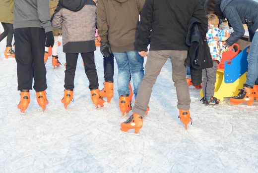 Ice skating youngsters on the skating rink in orange ice skates.