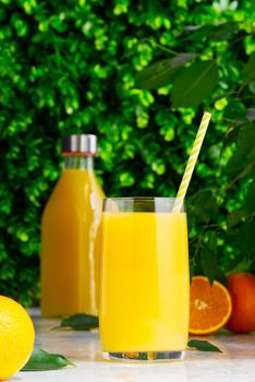 Glass of orange juice and orange juice bottle. Fresh tropical juice.