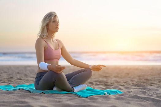Woman practice yoga lotus pose to meditation with summer vacation beach happiness and relaxation. Calm female exercise with yoga meditate ocean beach with sunset golden time.