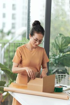 Young woman running online cosmetic store packing goods for dispatch