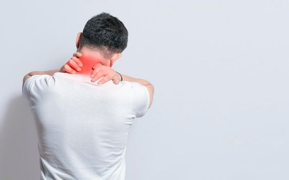 Close up of person with shoulder and neck problems, sore man touching his shoulder on isolated background, lumbar and muscular problems concept