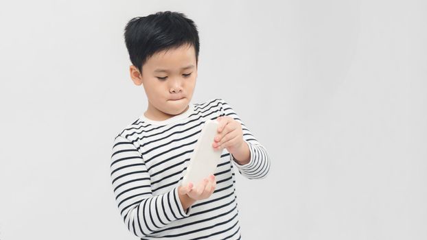  Asian child focused and concentrated playing with mobile phone  in kid suffering gaming addiction concept