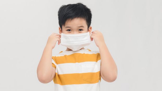 Cute little boy child wearing a protective face mask to prevent virus infection or pollution isolated over white background