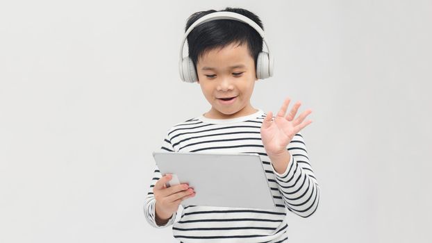 a lovely young pupil rejoicing and jumping with his tablet wearing headphones and smiling
