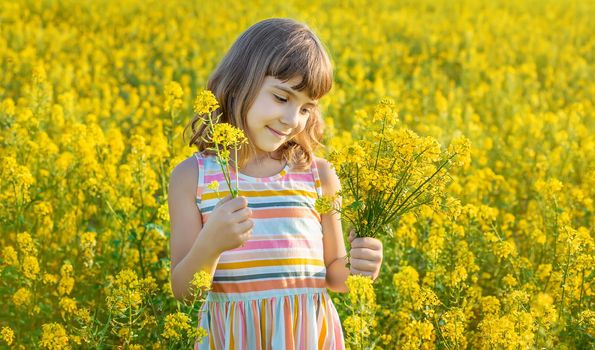 A child in a yellow field, mustard blooms. Selective focus.