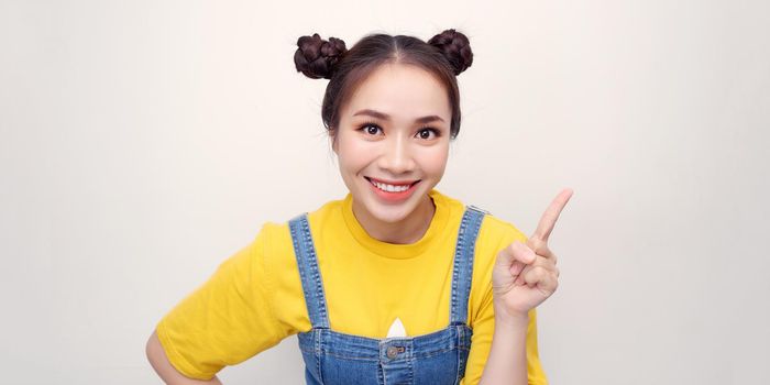 Portrait of Asian beautiful young woman pointing one hand with finger on upper left side with smile face. Advertisement & presentation concept.