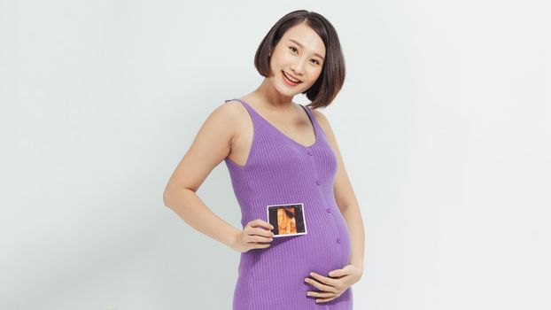 pregnant woman shows a ultrasound photo of her future baby.