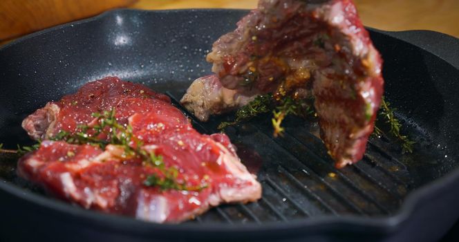 Appetizing Beef Steak cooking in a pan seasoned with herbs.