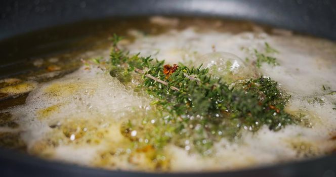 Cook in Pan. Frying Herbs Thyme with Butter for Meat
