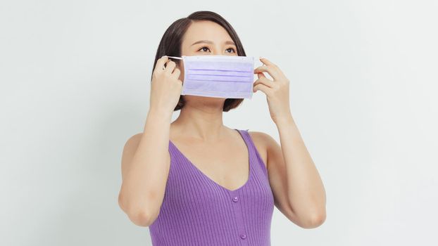 Young beautiful pregnant asian woman standing and touching belly  wearing virus protection mask mouth concept.