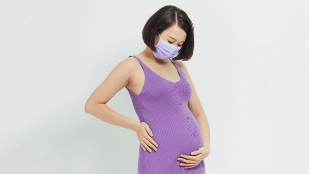 Healthcare concept.Asian pregnant woman in protective mask against flu and viruses, white background