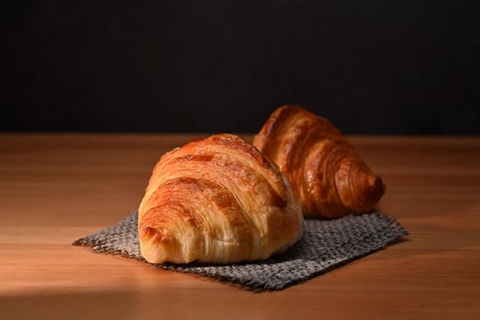 Tasty crusty butter croissants on wooden table. Breakfast, bread bakery products cafe concept