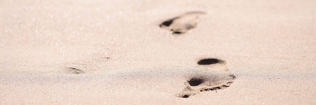 Barefoot prints on wet sand on beach closeup background