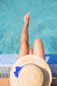 Beautiful girl in a hat near a blue pool - sun, summer, heat. Top view