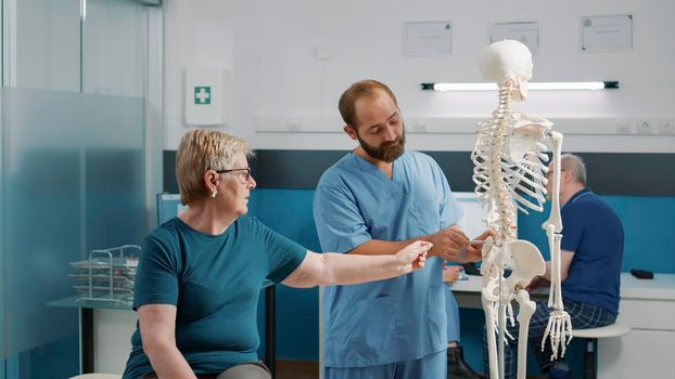 Osteopath explaining orthopedic diagnosis on human skeleton