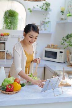 Young asian woman  preparing vegetables for salad at her kitchen