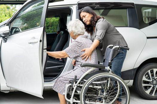 Caregiver daughter help and support asian senior or elderly old lady woman patient prepare get to her car.