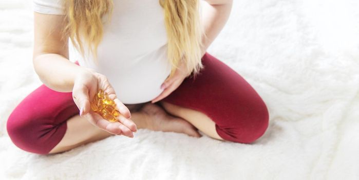 A pregnant woman drinks omega three vitamins. Selective Focus.