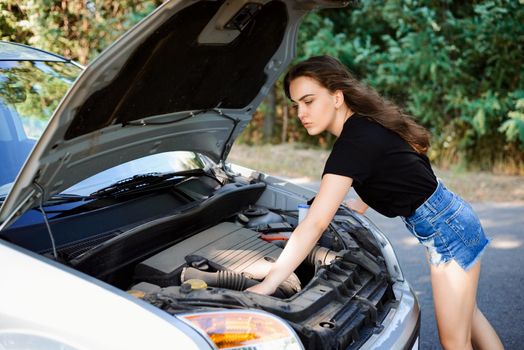 Young woman checks car engine