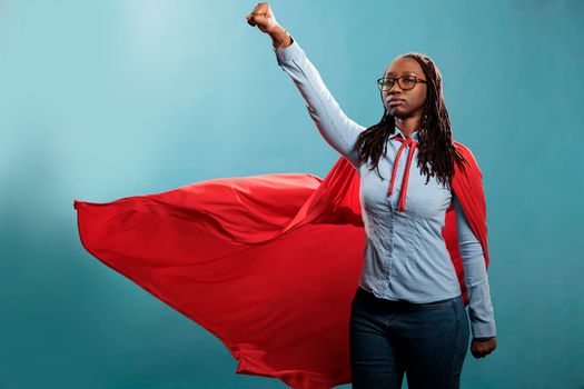 Powerful and brave young superhero woman wearing hero costume while posing as flying